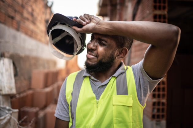 Exhausted construction worker wipes his forehead.